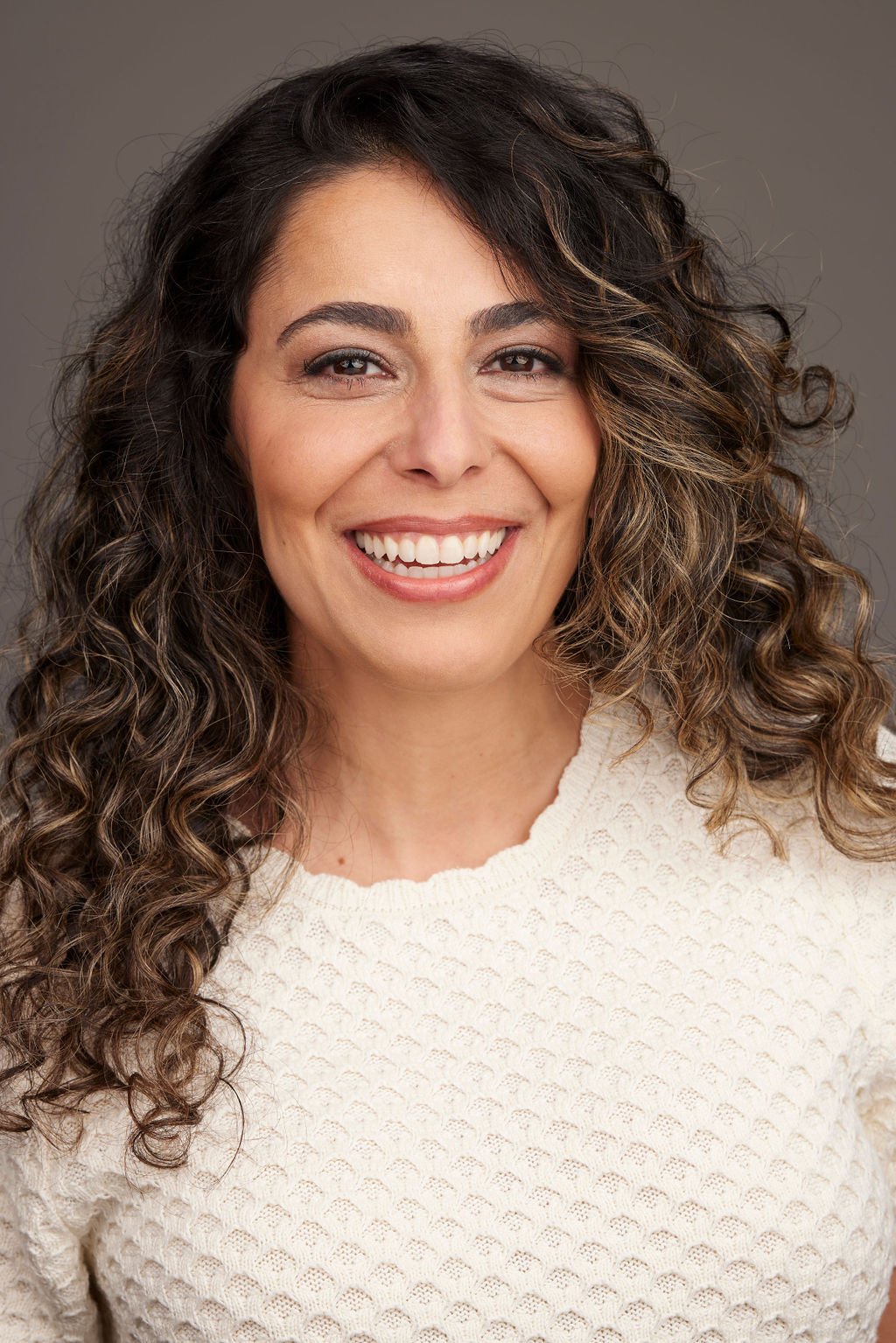 Azadeh Zanjani smiling headshot with long curly hair